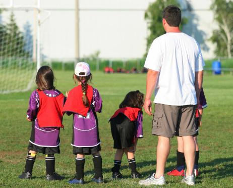 Kids with coach on soccer field